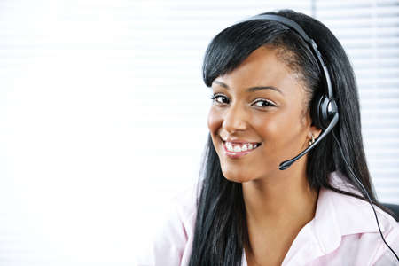 Smiling black customer service and support woman wearing headsetの写真素材