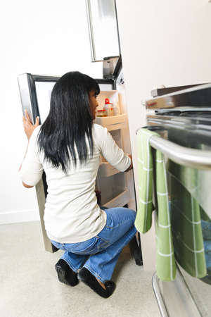 Black woman looking in fridge of modern kitchen interiorの写真素材