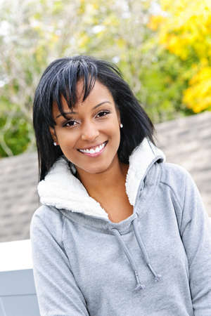 Portrait of happy smiling young black woman outside in the fallの写真素材
