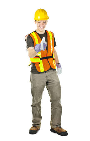 Smiling male construction worker showing thumbs up in safety vest and hard hatの写真素材
