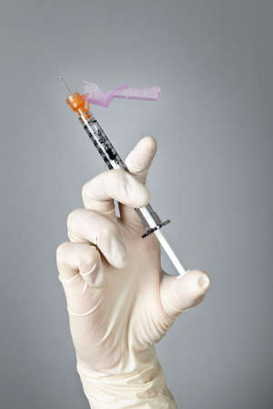 Medical safety syringe held by hand in surgical latex gloveの写真素材