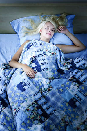 Young woman sleeping peacefully at night in bedの写真素材