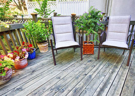Chairs and plants on wooden deck in backyard of homeの写真素材
