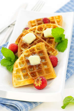 Plate of belgian waffles with fresh strawberries and pats of butterの写真素材