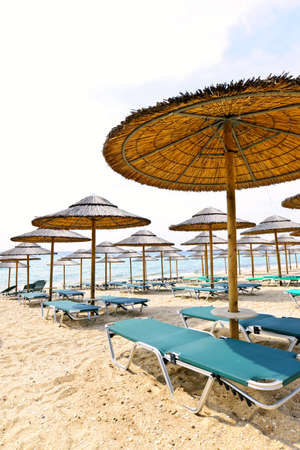 Straw umbrellas on empty seaside beach in Greece