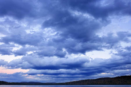 Blue cloudy dramatic sky at sunset over forest wilderness in Algonquin Park, Canada