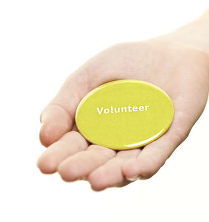 Hand holding green round volunteer button isolated on whiteの写真素材