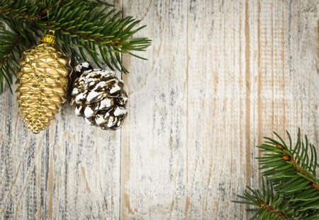 Christmas golden balls and pine cone on spruce branch with wooden backgroundの写真素材