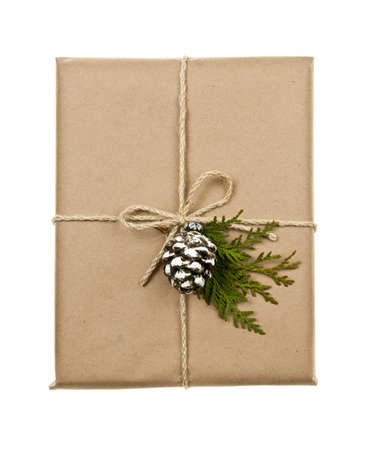 Christmas gift in brown wrapping and string with pine cone decoration isolated on whiteの写真素材