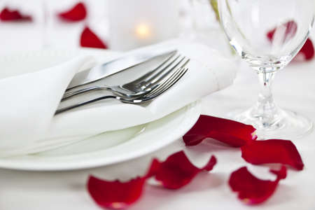 Romantic table setting with rose petals plates and cutleryの写真素材