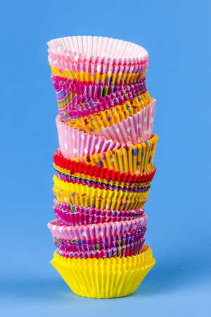 Tall stack of colorful muffin or cupcake cups on blue backgroundの写真素材