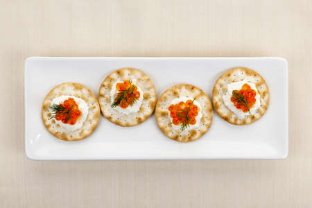 Caviar appetizer with goat cheese and crackers on white plate from aboveの写真素材