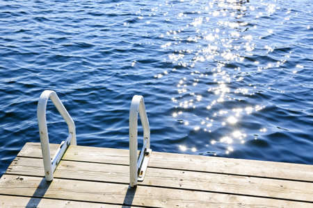 Dock and ladder on calm summer lake with sparkling water in Ontario Canadaの写真素材
