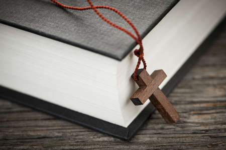 Closeup of wooden Christian cross necklace next to holy Bibleの写真素材