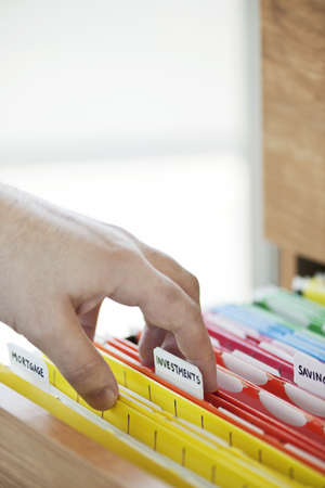 Hand searching through file folders with personal finance documentsの写真素材