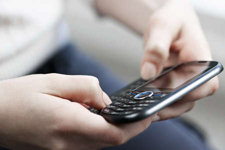 Female hands texting on slide-out keyboard of cellphone closeup