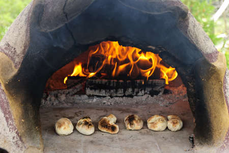 Stone wood oven with fire baking fresh homemade breadの写真素材