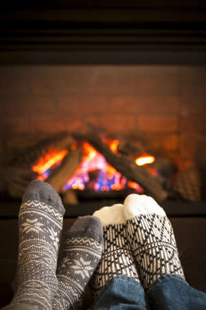 Feet in wool socks warming by cozy fireの写真素材