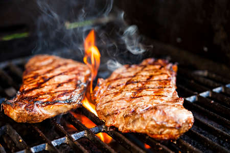 Beef steaks cooking in open flame on barbecue grillの写真素材
