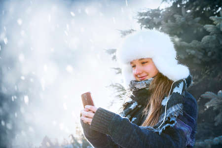 Portrait of teenage girl holding mobile phone outside in winterの写真素材