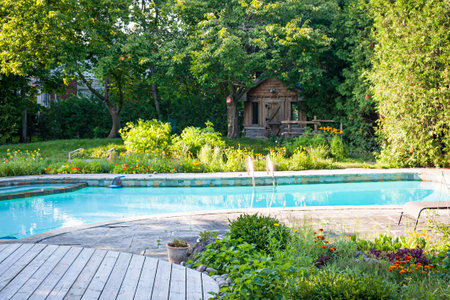 Backyard with garden, shed,  outdoor inground residential swimming pool, curved wooden deck and stone patioの写真素材