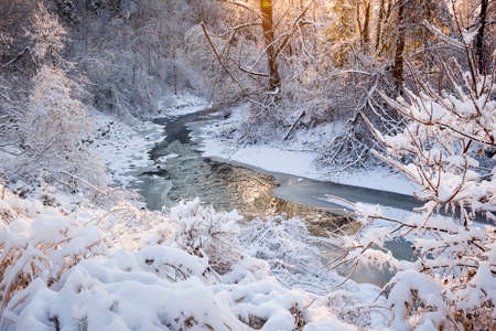 Winter landscape of snow covered forest with flowing river after winter snowstorm glowing and sparkling in warm sunshine. Ontario, Canada.の写真素材