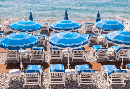 Blue umbrellas and chairs on pebble beach in Nice, France.の写真素材