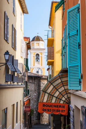 VILLEFRANCHE-SUR-MER, FRANCE - OCTOBER 4, 2014: Narrow street leading to Eglise Saint-Michel (Saint Michael's Church) is framed by colourful buildings and quaint shops.のeditorial素材