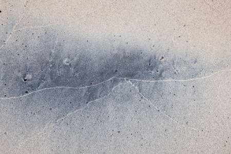 Grey and beige abstract background of wet sand texture formed by waves on beach