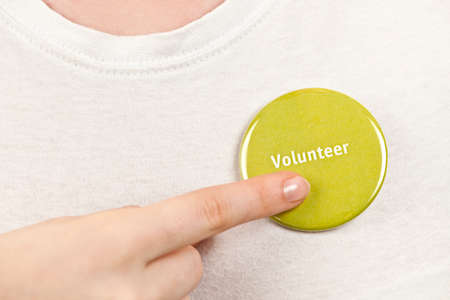 Closeup on female hand pointing to green volunteer buttonの写真素材