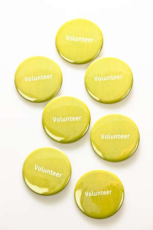 Several green volunteer buttons on white backgroundの写真素材