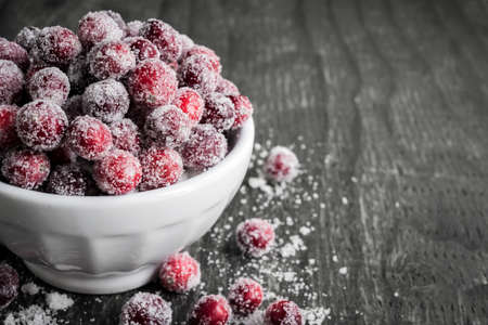 Sugared cranberries holiday dessert in bowl on rustic wooden background with copy spaceの写真素材