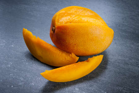Fresh cut mango fruit with slices on grey stone backgroundの写真素材