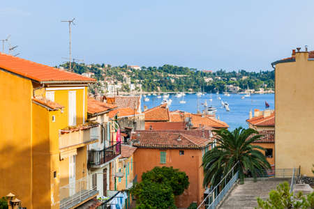 View of colorful rooftops and Mediterranean sea harbor with boats in old medieval town Villefranche-sur-Mer on French Riviera, France.の写真素材