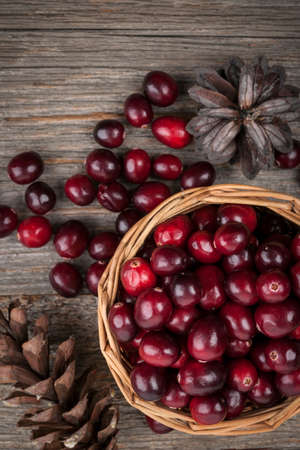 Fresh ripe cranberries in basket on rustic dark wooden background, overhead viewの写真素材