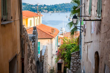 Narrow street with old buildings leading to Mediterranean sea in medieval town Villefranche-sur-Mer on French Riviera, France.の写真素材