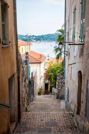 Narrow street with old buildings leading to Mediterranean sea in medieval town Villefranche-sur-Mer on French Riviera, France.の写真素材