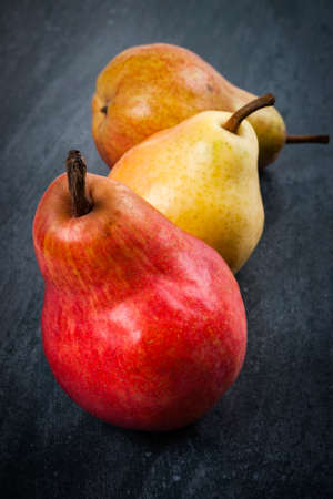 Three bright ripe bartlett pears on dark grey backgroundの写真素材