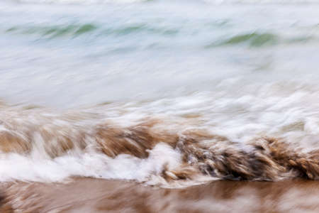 Ocean waves crashing on sandy beach abstract background, in-camera motion blur.の写真素材