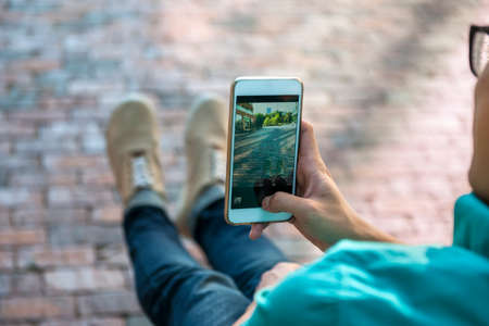 Young asian man taking photo of street and his feet with smartphoneの写真素材