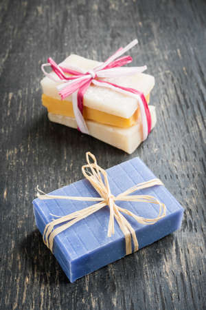 Colorful handmade soaps tied with strings on rustic wooden backgroundの写真素材