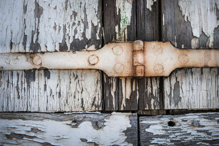 Detail of old wooden window shutters with rusty iron hinge and peeling paint. Toulouse, France.