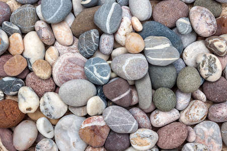 Small rounded beach pebbles or smooth rocks with various colors and shapes of stones, overhead view.の写真素材