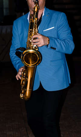 Saxophonist. A musician in a jacket plays a melody on a saxophone. Musical instrument. Jazz.