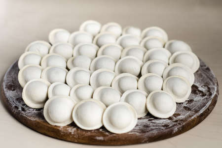 Raw dumplings on a round Board, top view. A traditional Slavic dish. Russian national food. The process of cooking dumplings. Traditional home-made food. Dough from flour for dumplings.の写真素材