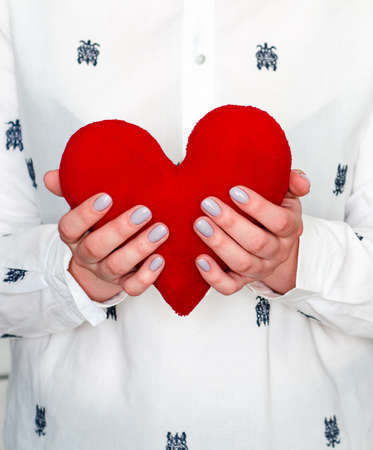 Red soft heart in women's hands. Love. Attachment.の写真素材