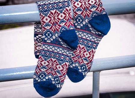 Beautiful warm knitted socks hang on railing. Knee socks with ornaments. Rustic retro style in clothing.の写真素材