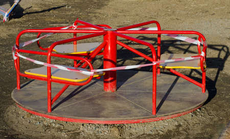 children's carousel on street Playground is wrapped with forbidding striped tape. Quarantine. Ban on walking.の写真素材
