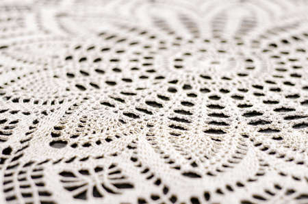 Beautiful knitted pattern close-up. Lace knitted fabric made of white thread. Handmade items. The texture is knitted from threads.の写真素材