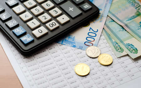 On top of printed payment schedule-Russian cash and black calculator. Payment of bills. Family budget.の写真素材